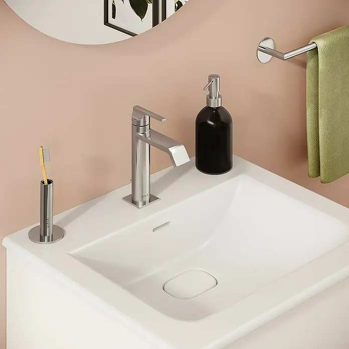 VitrA Suit Waschtischarmatur - Chrom, Glänzend, Höhe: 19 cm - Moderner Badezimmerwaschtisch mit weißem Waschbecken, Chromarmatur, schwarzem Seifenspender, Zahnbürste und grünem Handtuch an einer Stange.