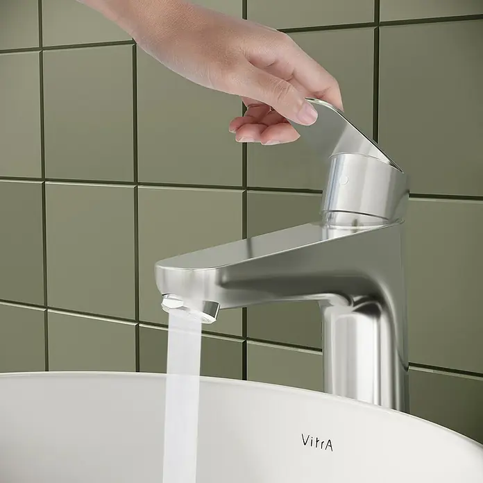 VitrA Flow Round Waschtischarmatur - Höhe: 27 cm, Ausladung Armatur: 151 mm, Chrom, Mit Zugstange - Hand dreht modernen Chrom-Wasserhahn auf, Wasser fließt in weißes Waschbecken.