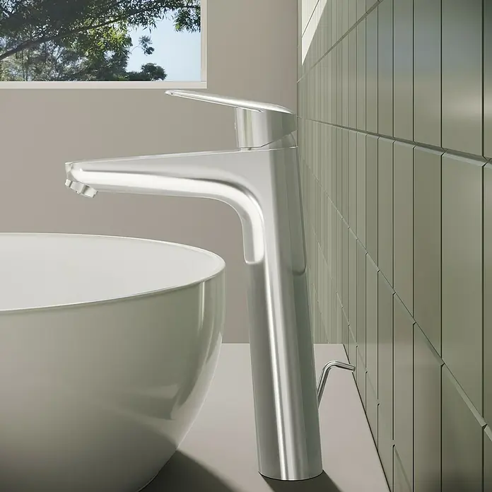 VitrA Flow Round Waschtischarmatur - Höhe: 27 cm, Ausladung Armatur: 151 mm, Chrom, Mit Zugstange - Ein eleganter Chrom-Badarmatur steht neben einem weißen Aufsatzwaschbecken. Sonnenlicht fällt auf die grüne Fliesenwand.