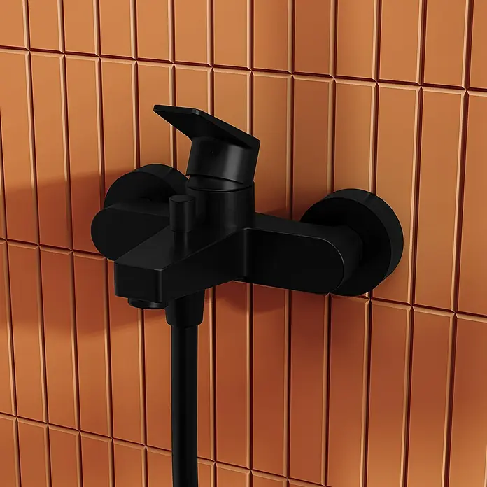VitrA Flow Square Badewannenarmatur - Schwarz, Matt - Mattschwarze Duscharmatur mit Schlauch an einer terrakottafarbenen Fliesenwand.