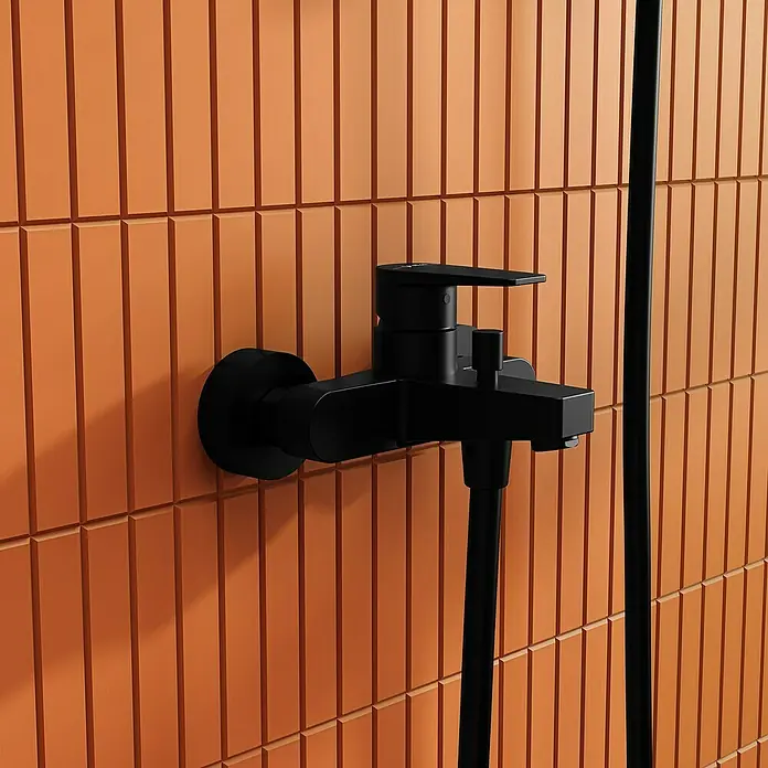 VitrA Flow Square Badewannenarmatur - Schwarz, Matt - Mattschwarze Duscharmatur an einer orangefarbenen Fliesenwand, mit einem schwarzen Duschschlauch darunter.