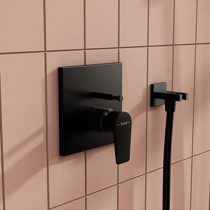 VitrA Flow Square UP-Badewannenarmatur - Ausladung Armatur: 90 mm, Schwarz, Matt - Mattschwarze Duscharmatur und Schlauchhalter an einer rosa Fliesenwand.