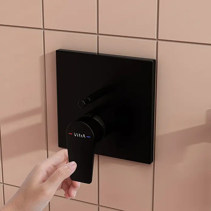 VitrA Flow Square UP-Badewannenarmatur - Ausladung Armatur: 90 mm, Schwarz, Matt - Hand verstellt schwarze VitrA Duscharmatur vor pfirsichfarbener Fliesenwand.