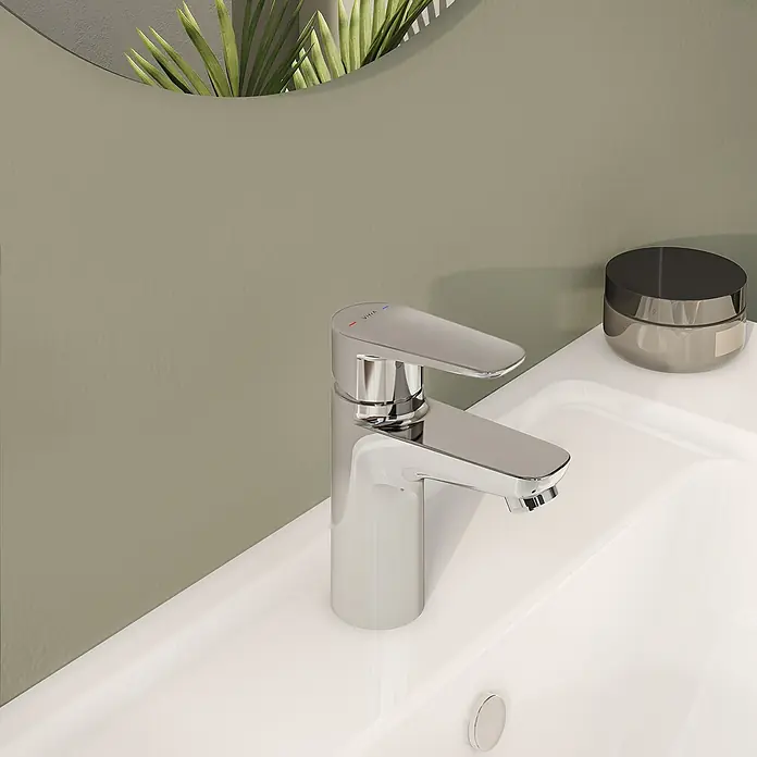 VitrA Flow Soft Waschtischarmatur - Chrom, Höhe: 15 cm, Ohne Zugstange - Verchromte Einhebelarmatur mit VitrA-Branding und Warm-/Kaltanzeigen, auf einem weißen Keramikwaschbecken montiert.