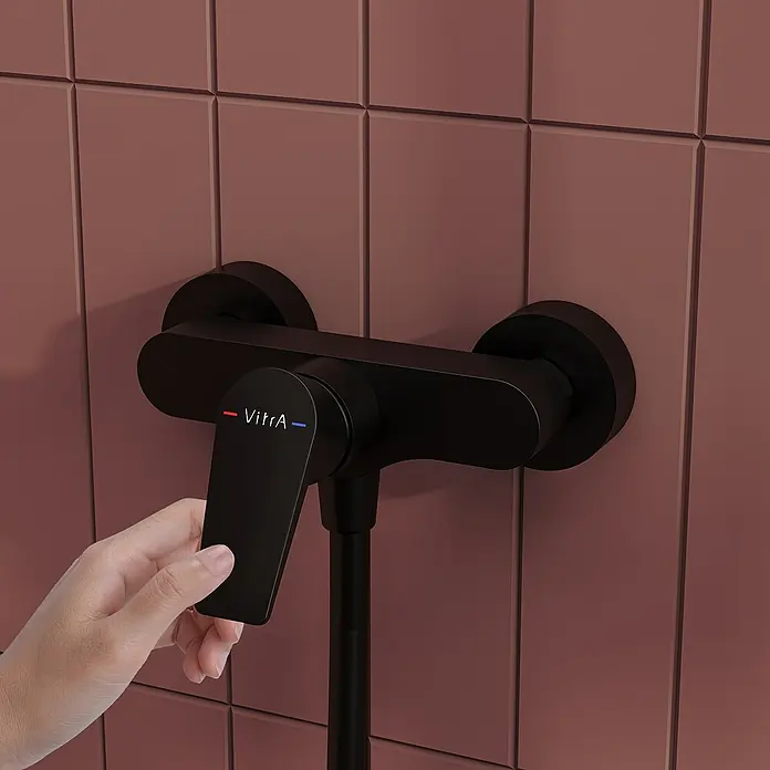 VitrA Flow Square Brausearmatur - Ausladung: 12,7 cm, Schwarz, Matt - Hand verstellt schwarzen VitrA Duschmischer an einer gefliesten Wand.