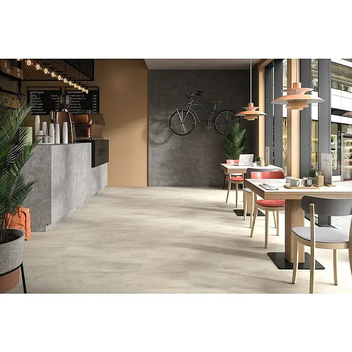 Egger Laminat Aquadura+ - Chromix weiss, 1.292 x 327 x 7,5 mm - Innenaufnahme eines Cafés mit Holztischen und Stühlen, stilvoller Einrichtung und modernen Pendelleuchten.