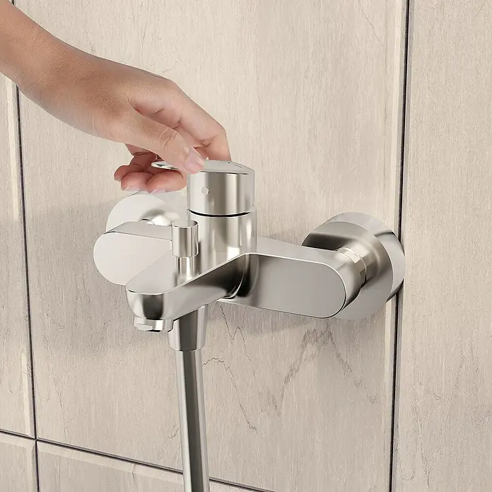 VitrA Flow Round Badewannenarmatur - Chrom, Glänzend - Eine Hand verstellt eine moderne Chrom-Duscharmatur an einer hellen Fliesenwand.