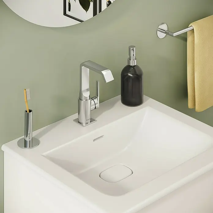 VitrA Suit Waschtischarmatur - Chrom, Glänzend, Mit Zugstange, Höhe: 20,6 cm - Modernes weißes Waschbecken mit Chromarmatur, schwarzem Seifenspender, Zahnbürstenhalter und gelbem Handtuch.