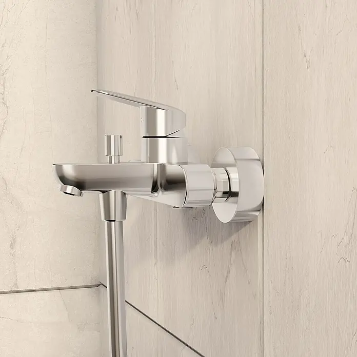 VitrA Flow Round Badewannenarmatur - Chrom, Glänzend - Verchromte Duscharmatur mit Auslauf und Brauseschlauchanschluss, an hellen Badezimmerfliesen montiert.