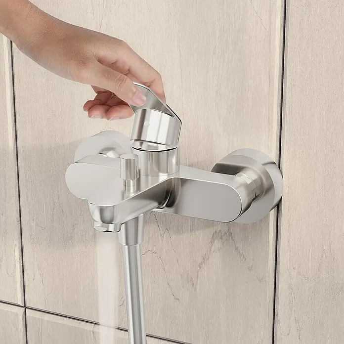 VitrA Flow Round Badewannenarmatur - Chrom, Glänzend - Hand betätigt eine elegante Chrom-Duscharmatur an hellen Holzoptikfliesen.