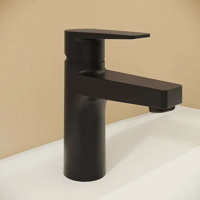 VitrA Flow Square Waschtischarmatur - Schwarz, Matt, Höhe: 15,6 cm, Mit Zugstange - Mattschwarzer Wasserhahn auf einem weißen Waschbecken vor einer beigen Wand.