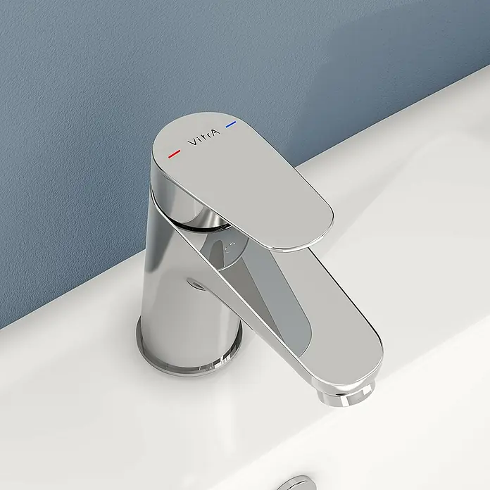VitrA Flow Round Waschtischarmatur - Höhe: 15 cm, Ausladung Armatur: 114 mm, Chrom, Ohne Zugstange - Verchromte VitrA Einhebel-Waschtischarmatur mit rot/blau Heiß/Kalt-Indikatoren auf einem weißen Waschbecken.