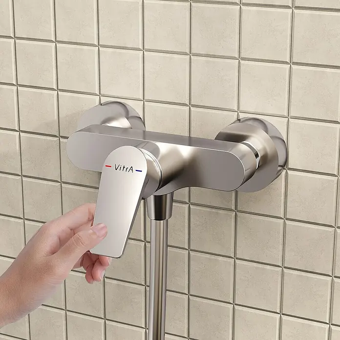 VitrA Flow Square Brausearmatur - Ausladung: 12,7 cm, Chom, Glänzend - Hand bedient den Hebel einer silbernen VitrA Duscharmatur an einer gefliesten Wand.