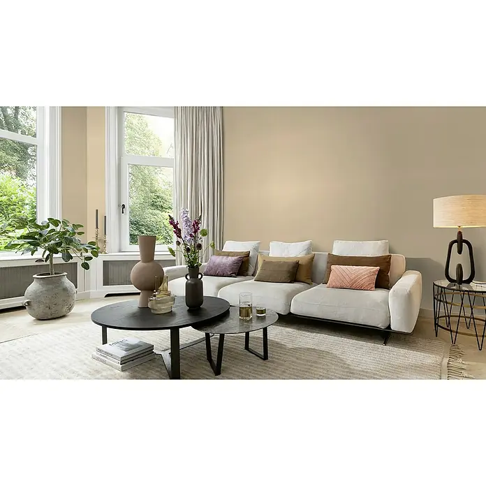 Rasch Incanto Vliestapete - Apricotbeige, Uni, 10,05 x 0,53 m - Elegantes Wohnzimmer mit bequemer Couch, dekorativen Kissen und stilvoller Beleuchtung, die eine warme Atmosphäre schaffen.