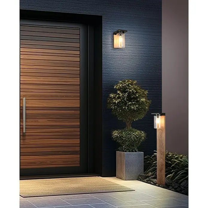 Trio Lighting Aplique exterior Ardila - 40 W, 11 x 19 cm, Marrón, IP44 - Una moderna puerta de entrada de madera con iluminación exterior elegante crea un ambiente acogedor en el entorno exterior.