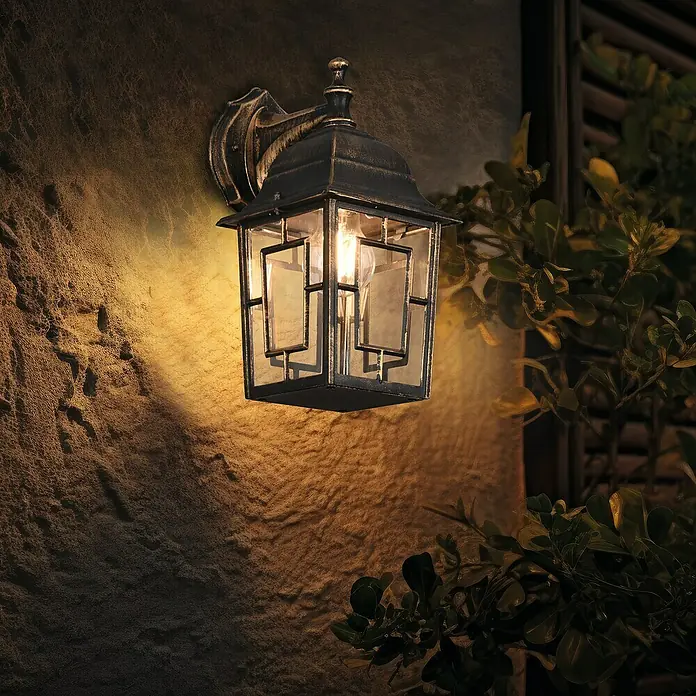 Trio Lighting Aplique exterior Volturno - 60 W, 19 x 15 x 30 cm, Bronce, IP44 - Primer plano de un farol de pared clásico con detalles dorados que crea un ambiente cálido.