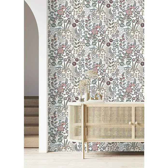 Rasch Selection Vliestapete Vinyl - Pastell/Hellrosa, Floral, 10,05 x 0,53 m - Nahaufnahme einer Kommode mit Rattangeflecht vor einer Wand mit floralem Muster, die eine warme und einladende Atmosphäre schafft.
