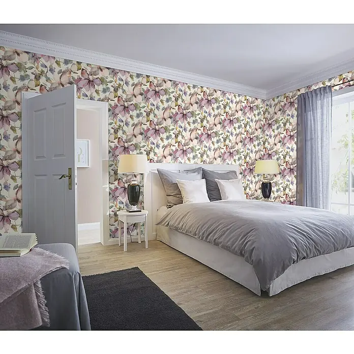 Rasch Florentine IV Vliestapete Flowers - Pastellpink, Floral, 10,05 x 0,53 m - Schlafzimmer mit floral gemusterter Tapete, einem Bett mit grauer Bettwäsche, Nachttisch und einer offenen Tür, die in ein anderes Zimmer führt.