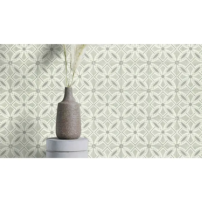Rasch Beachhouse Vliestapete Fliesenkacheln - Graugrün, Fliesenoptik, 10,05 x 0,53 m - Nahaufnahme von gemusterten Vintage-Fliesen in neutralen Farben mit einer braunen Vase und Dekoration auf einem grauen Sockel für ein elegantes Ambiente.