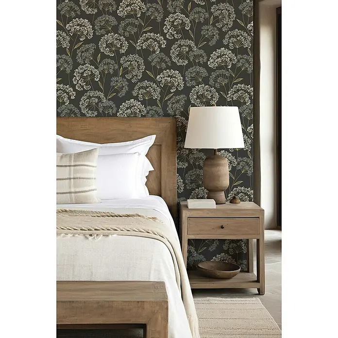 Rasch Selection Vliestapete Vinyl Blümchen - Mattschwarz, Floral, 10,05 x 0,53 m - Schlafzimmer mit einem Holzbett, Nachttisch und einer Lampe vor einer Wand mit Blumenmuster.