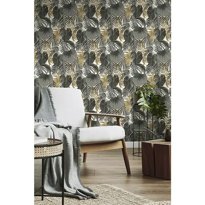 Rasch Selection Vliestapete Vinyl Blätter - Schwarz/Gold, Floral, 10,05 x 0,53 m - Tropische Tapete mit grauen und goldenen Blättern als stimmungsvoller Hintergrund für einen modernen Wohnraum mit Sessel und Holztisch.
