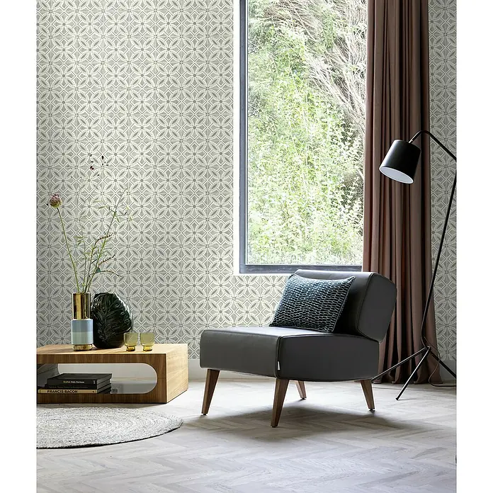 Rasch Beachhouse Vliestapete Fliesenkacheln - Hellgrau, Fliesenoptik, 10,05 x 0,53 m - Elegantes Wohnzimmer mit einem grauen Sessel mit Kissen, einem Holztisch und einer Stehlampe vor einem Fenster.