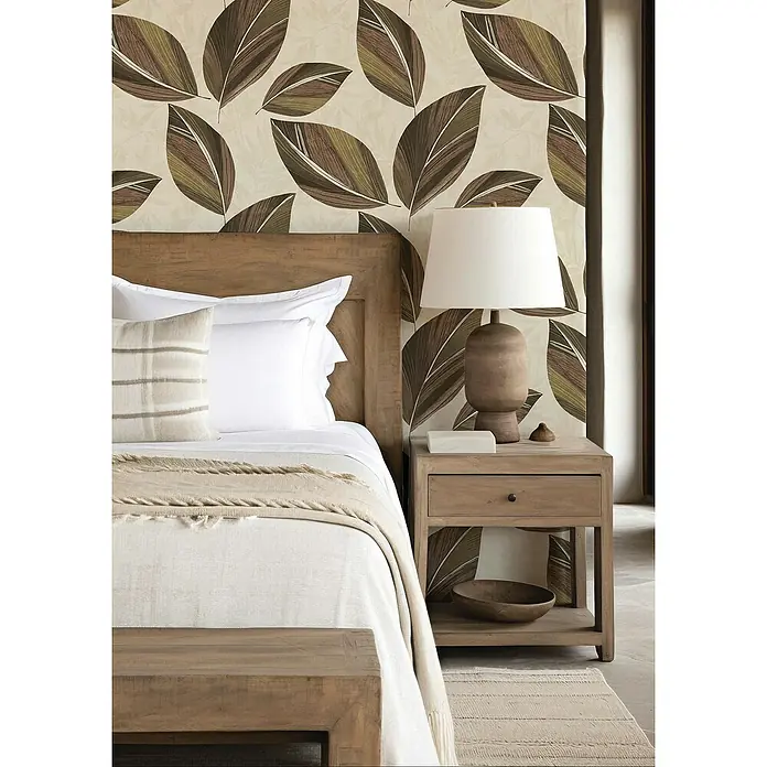 Rasch Selection Vliestapete Vinyl Botanical - Rotbraun/Beige, Floral, 10,05 x 0,53 m - Schlafzimmer-Szene mit einem Holzbett, Nachttischlampe und Blattmuster-Tapete, die eine gemütliche und natürliche Atmosphäre schaffen.