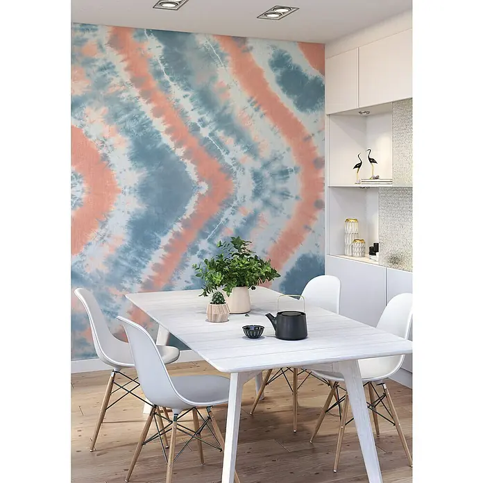 Rasch Beachhouse Fototapete Batikoptik I - B x H: 300 x 265 cm, Vlies, Blau - Esstisch mit vier Stühlen, Geschirr und Pflanzendekoration vor einer Wand mit Batikmuster in einem modernen Esszimmer.