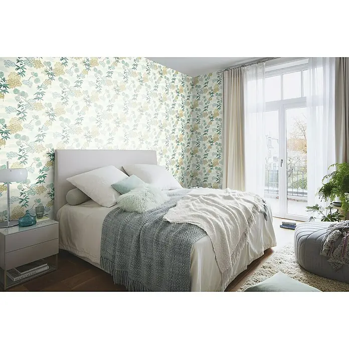 Rasch Selection Vliestapete Vinyl Botanical - Pastelltürkis/Goldbeige, Floral, 10,05 x 0,53 m - Ein Schlafzimmer mit einem Bett, Nachttisch und floraler Tapete. Das Bett ist mit Kissen und einer Decke bedeckt, was eine gemütliche Atmosphäre schafft.