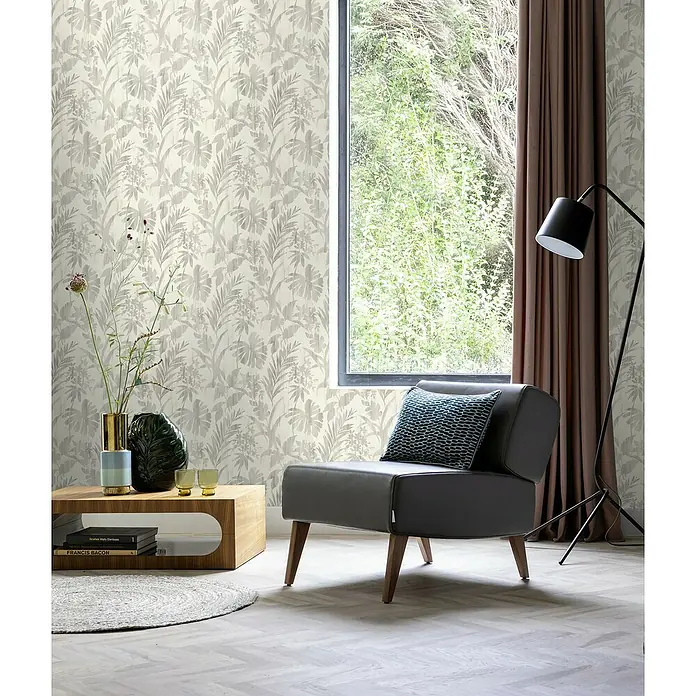 Rasch Beachhouse Vliestapete Pastelles Pflanzenmotiv - Hellgrau, Floral, 10,05 x 0,53 m - Wohnzimmer Interieur mit grauem Sessel und einem floralen Tapetenmuster, das dem Raum eine ruhige, stilvolle Atmosphäre verleiht.