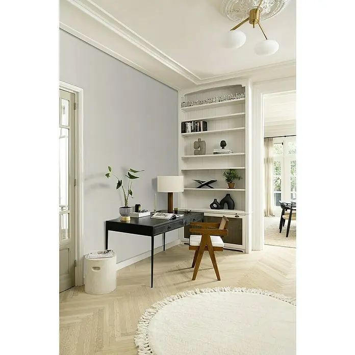 Rasch Beachhouse Vliestapete Modern - Graubeige, Uni, 10,05 x 0,53 m - Ein elegantes Heimbüro mit schwarzem Schreibtisch, Holzstuhl und einem runden, weißen Teppich, der eine stilvolle und einladende Atmosphäre schafft.
