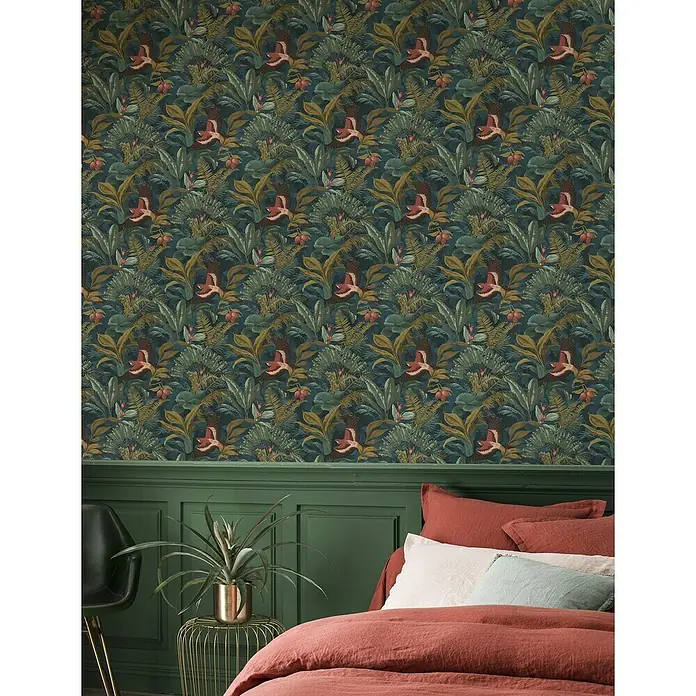 Rasch Selection Vliestapete Vinyl Dschungeltapete - Bunt, Floral, 10,05 x 0,53 m - Schlafzimmer mit gemusterter Dschungeltapete, Bett mit orangefarbener Bettwäsche und grüner Wandvertäfelung für ein gemütliches Ambiente.