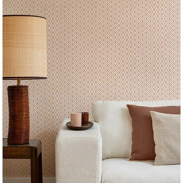 Rasch Beachhouse Vliestapete Allover-Design - Rosa, Grafisch, 10,05 x 0,53 m - Nahaufnahme eines gemütlichen Wohnzimmers mit einer Lampe, einem Tisch und einem Sofa mit Kissen.