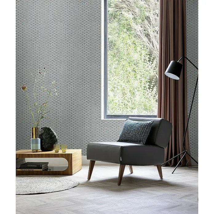 Rasch Beachhouse Vliestapete Allover-Design - Blaugrau, Grafisch, 10,05 x 0,53 m - Einrichtungsidee mit einem stilvollen grauen Sessel, Couchtisch und Stehlampe vor einer gemusterten Wand.
