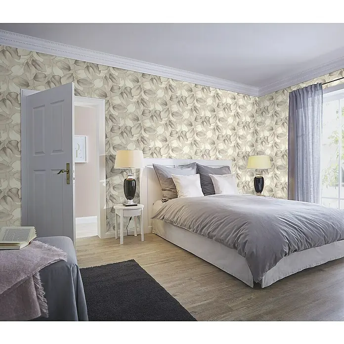 Rasch Incanto Vliestapete Moderne Blätter - Beige/Grau, Floral, 10,05 x 0,53 m - Schlafzimmer mit einem großen Bett, das mit grauer Bettwäsche und weißen Kissen ausgestattet ist. Die Wände sind mit einer Blümchentapete dekoriert.
