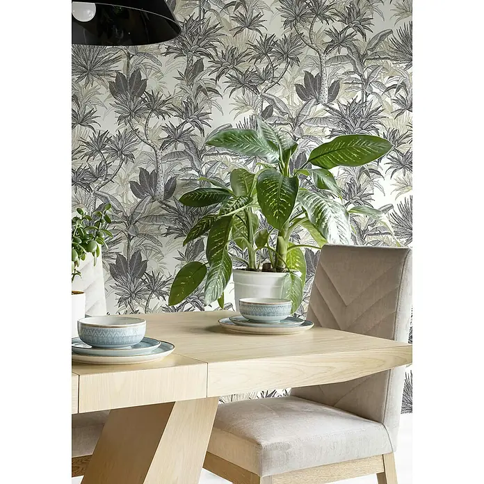 Rasch Selection Vliestapete Vinyl Botanical - Schwarz/Weiß, Floral, 10,05 x 0,53 m - Ein heller Esstisch mit zwei Stühlen, Geschirr und einer Zimmerpflanze auf einer stilvollen Oberfläche mit tropischer Tapete.