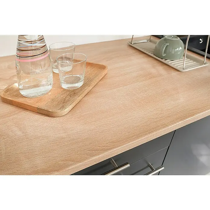 Respekta Merle Unterschrank - B x T x H: 150 x 60 x 85 cm, Grau - Nahaufnahme einer Arbeitsplatte mit Wasserflasche, Gläsern und Abtropfgestell, die die Holzmaserung und die Kücheneinrichtung zeigt.