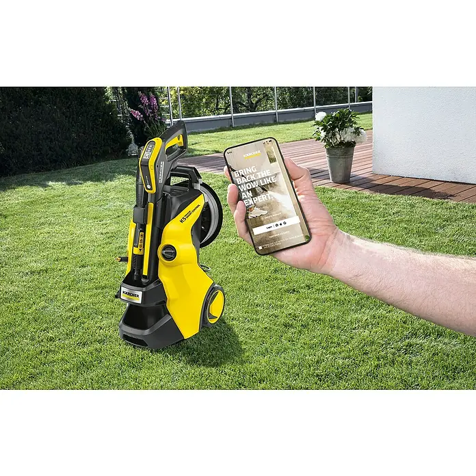 Kärcher Hochdruckreiniger K 5 Premium Smart Control Flex - 2.100 W, Betriebsdruck: 20 bar - 145 bar, Fördermenge: 500 l/h, 5 -tlg. - Ein gelb-schwarzer Kärcher Hochdruckreiniger K5 und ein Smartphone mit der Kärcher App im Garten.