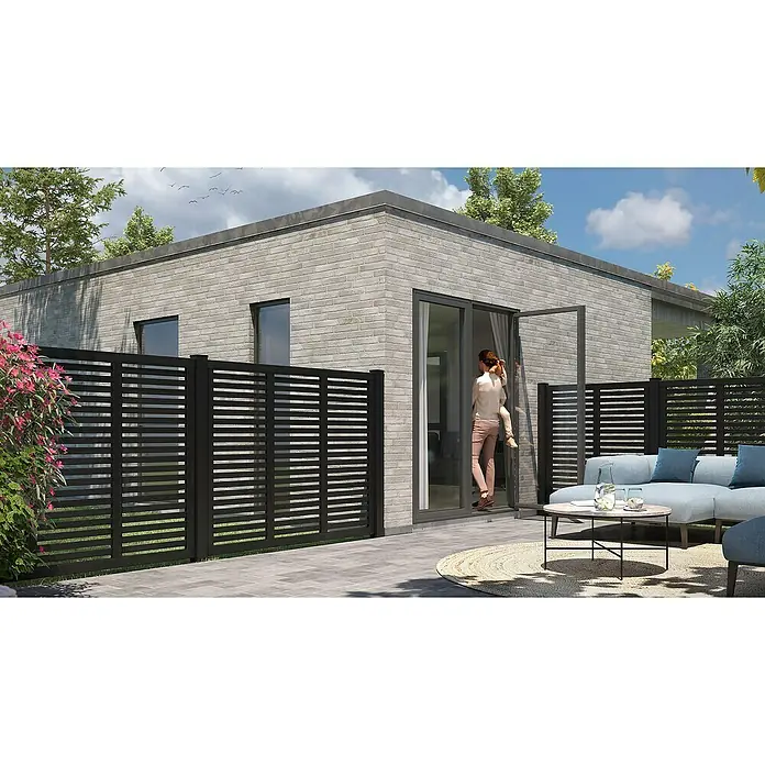 Plus Pfostenkappe Classic - 9,1 x 9,1 cm - Moderne Gartengestaltung mit grauem Ziegelhaus, schwarzem Zaun und stilvollem Outdoor-Möbelset.  Frau mit Kind betritt das Haus.