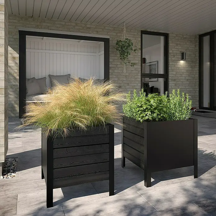 Plus Pflanzkasten Cubic - Außenmaß (L x B x H): 83 x 46 x 46,5 cm, Holz, Schwarz - Zwei schwarze Outdoor-Pflanzgefäße, eines mit Lattenholzstruktur, eines glatt, gefüllt mit üppigen Pflanzen auf einer modernen Terrasse.