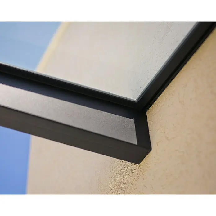 Palram – Canopia Pultvordach Sophia - 120 x 80 x 17 cm, Anthrazitgrau, Farbe Dach: Klar - Nahaufnahme eines modernen schwarzen Fensterrahmens an einer strukturierten, beigen Wand, der architektonische Details und hochwertige Bauweise hervorhebt.