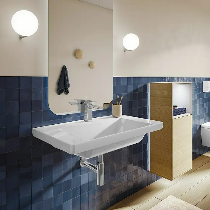 Villeroy & Boch Subway 3.0 Aufsatzwaschbecken - 80 x 47 cm, Mit schmutzabweisender Glasur, Ohne Überlauf, Stone White, Anzahl Hahnlöcher: 1 - Modernes Bad mit weißem Keramikwaschbecken, Chromarmatur, großem Spiegel, kugelförmigen Wandleuchten über blauen Fliesen und einem Holzschrank.