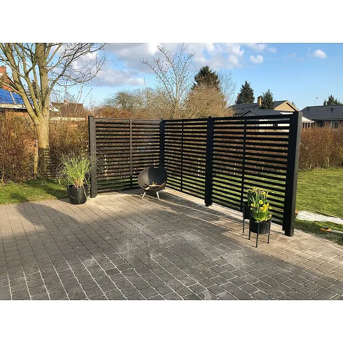 Plus Sichtschutzelement Koyto - 160 x 160 cm, Holz, Schwarz - Moderne Gartengestaltung mit einem stilvollen Sichtschutz aus dunklem Holz, ergänzt durch dekorative Pflanzkübel und eine Feuerstelle.