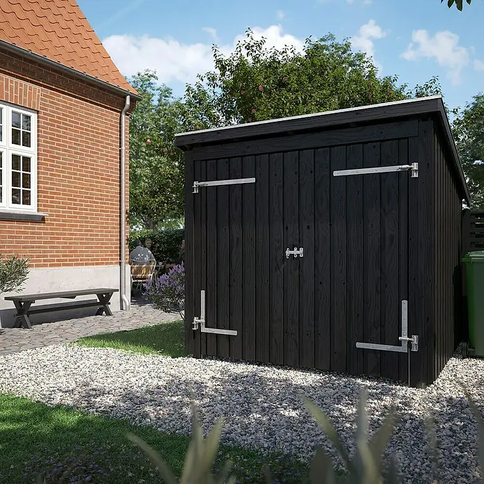 Plus Universal-Unterstand Nordic Für Fahrräder - Holz, Doppeltür inkl. Dachpappe und Aluleisten - Schwarzer Holzgartenschuppen mit verzinkten Metallscharnieren und -riegeln, in einem Kies- und Rasengarten neben einem Backsteinhaus.
