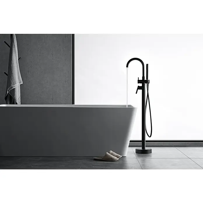IO Round Grifo para bañera exenta - Negro, Mate - Un grifo de bañera independiente en negro, situado junto a una bañera moderna con agua fluyendo.