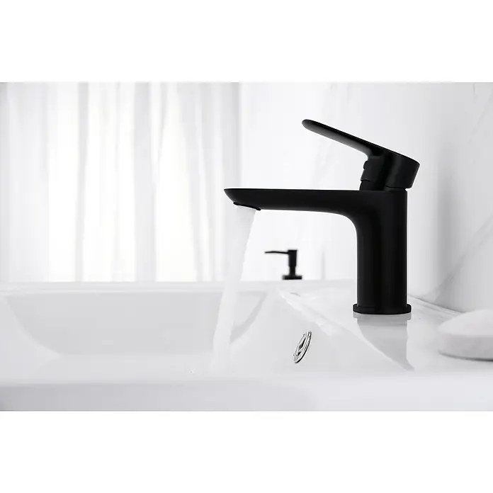 IO Cassio Grifo de lavabo - Negro - Primer plano de un grifo negro moderno con agua corriente en un lavabo, sobre un fondo luminoso.
