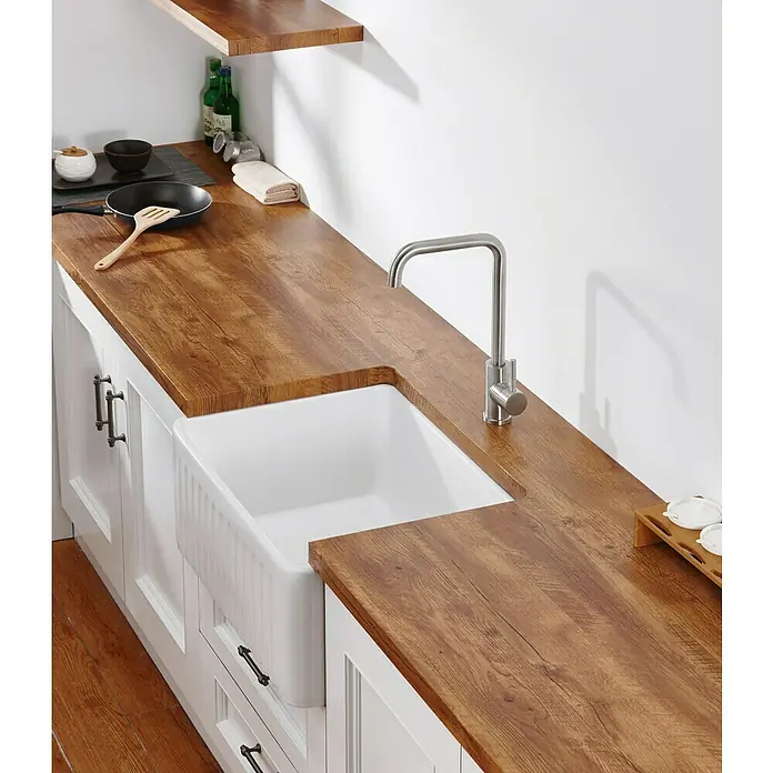 IO Grifo de cocina Noah - Acero, Satinado - Primer plano de una cocina de campo moderna con un fregadero blanco y un grifo de acero inoxidable sobre una encimera de aspecto de madera.