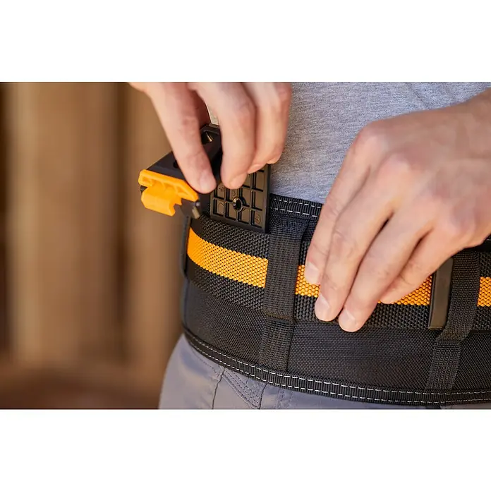 ToughBuilt ClipTech Systemverbinder - L x B x H: 2,5 x 5,3 x 8,1 cm, ABS, 3 Stk. - Der Mann befestigt das Tragesystem mit einem orangefarbenen Akzent an seinem Gürtel. Das Tragesystem dient zum Tragen von Werkzeugen und Zubehör.
