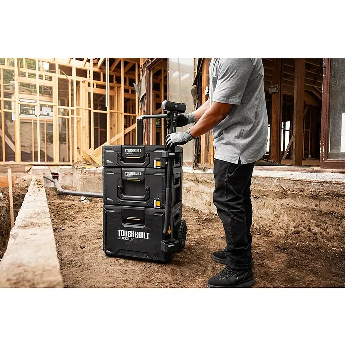 ToughBuilt StackTech Werkzeughalter - L x B x H: 11 x 8,4 x 9,3 cm, 2 -tlg. - Ein Handwerker schiebt ein ToughBuilt StackTech Werkzeugkoffersystem auf einer Baustelle.