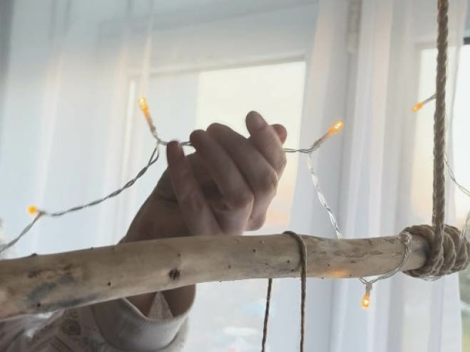 Lichterkette wird um einen Deko Ast gewickelt